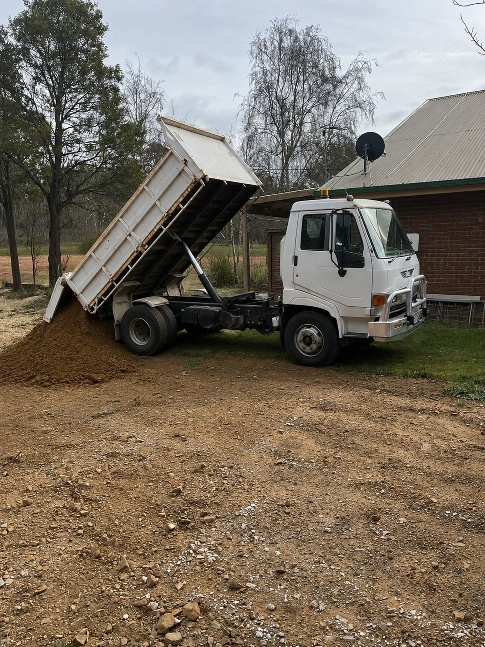 Monaro Earthworks tipper unloading material at a rural site near Adaminaby
